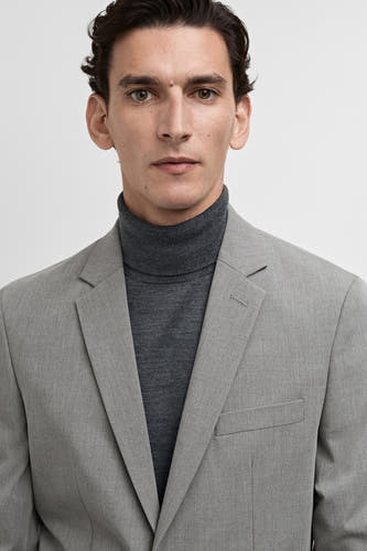 Grijze blazer van MANGO, gedragen met een grijze coltrui.
