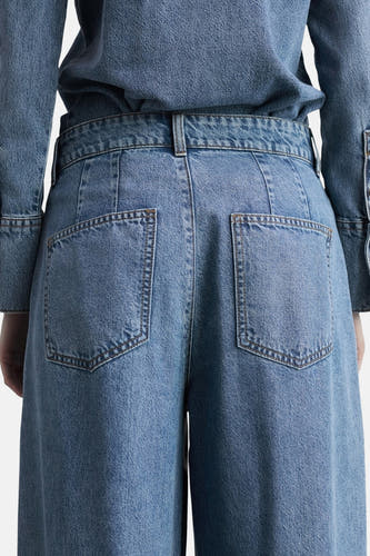 Jean décontracté en denim bleu moyen de MANGO, vu de derrière avec des poches droites et des passants.