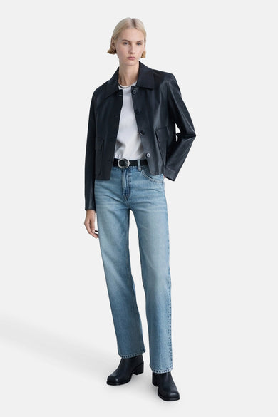 Lichtblauwe rechte jeans van MANGO, gedragen met een riem, een wit T-shirt en een donkerblauwe leren jas.