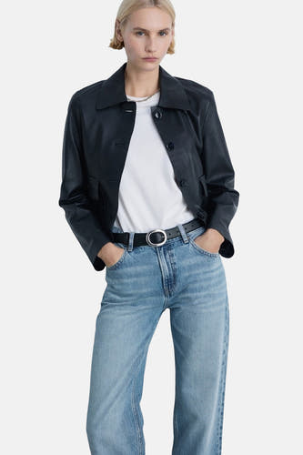 Jean droit bleu clair de MANGO, associé à un T-shirt blanc, un blazer en cuir noir et une ceinture noire avec une boucle argentée.