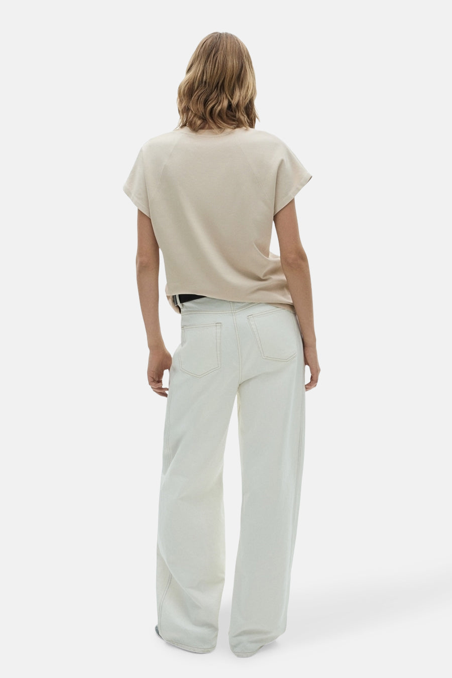 T-shirt beige à manches courtes de MANGO, vu de derrière, associé à un jean blanc et une ceinture noire.