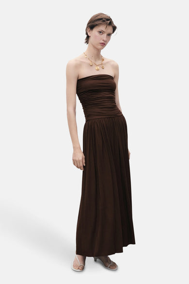 Bruine mouwloze jurk van MANGO, met een geplooide taille en een gouden ketting.
