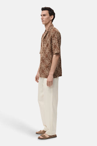 Chemise brune à manches courtes de MANGO, avec un joli motif et portée avec une légère jupe et des sandales.