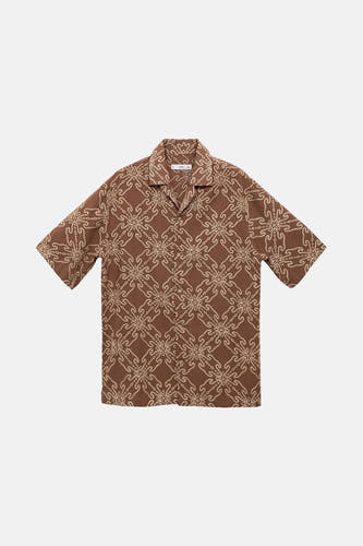 Chemise brune à manches courtes de MANGO, avec un motif de fleurs frappant et une encolure ouverte.