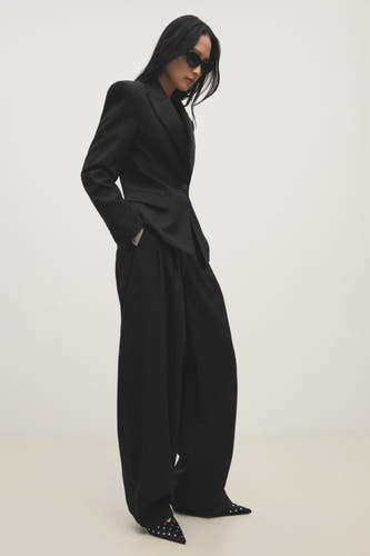 Des bottes multicolores de MANGO, ornées de strass argentés, portées avec un pantalon noir et un blazer.