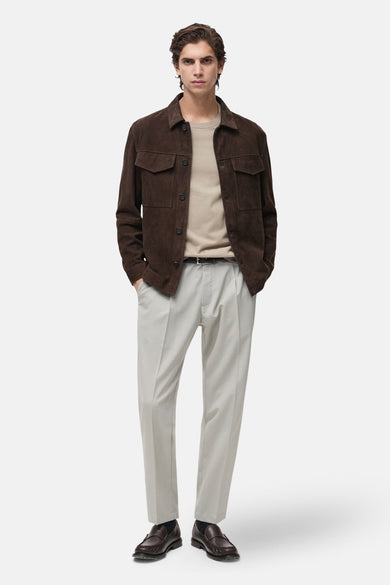 Beige T-shirt met korte mouwen van MANGO, gedragen onder een bruin jasje met lichtgrijze pantalon en bruine loafers.