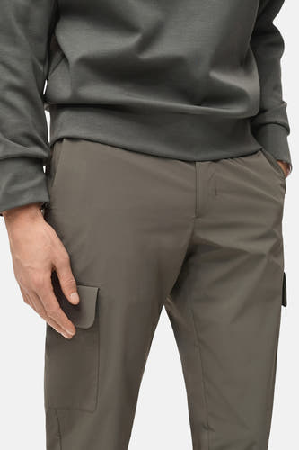 Pantalon vert MANGO, avec poches et une coupe décontractée, porté avec un sweat-shirt gris foncé.