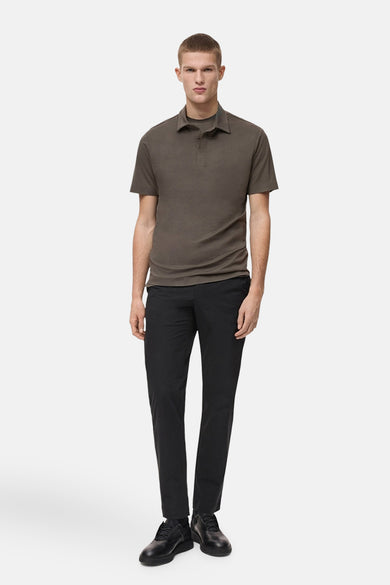 Kaki polo avec des manches courtes de MANGO, porté avec un pantalon foncé et des chaussures noires.