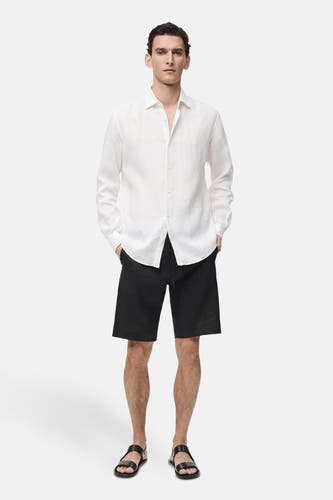 Zwarte short van MANGO, gedragen met een wit linnen overhemd en lederen sandalen.