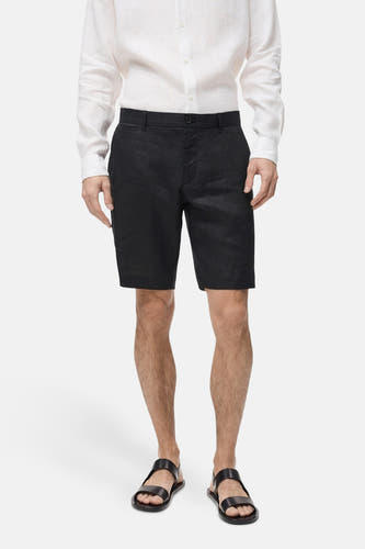 Zwarte short van MANGO, gedragen met een wit linnen overhemd en zwarte sandalen.