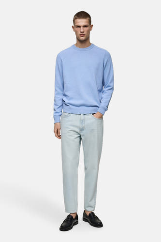Lichtblauwe tapered jeans van MANGO, gecombineerd met een lichtblauwe trui en zwarte schoenen.
