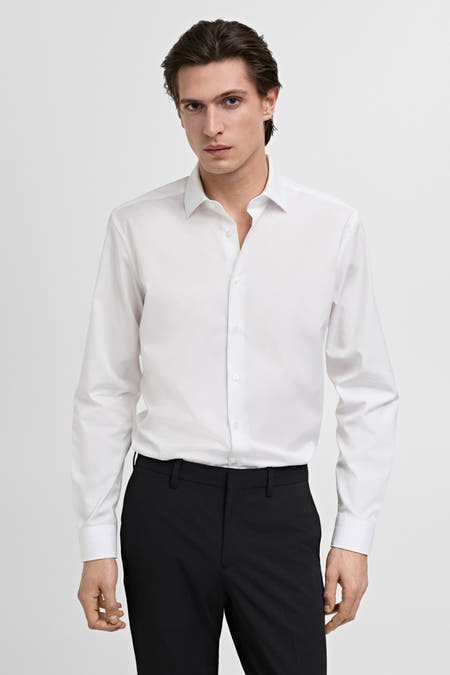 Wit overhemd met lange mouwen van MANGO, gecombineerd met een zwarte pantalon tegen een effen witte achtergrond.
