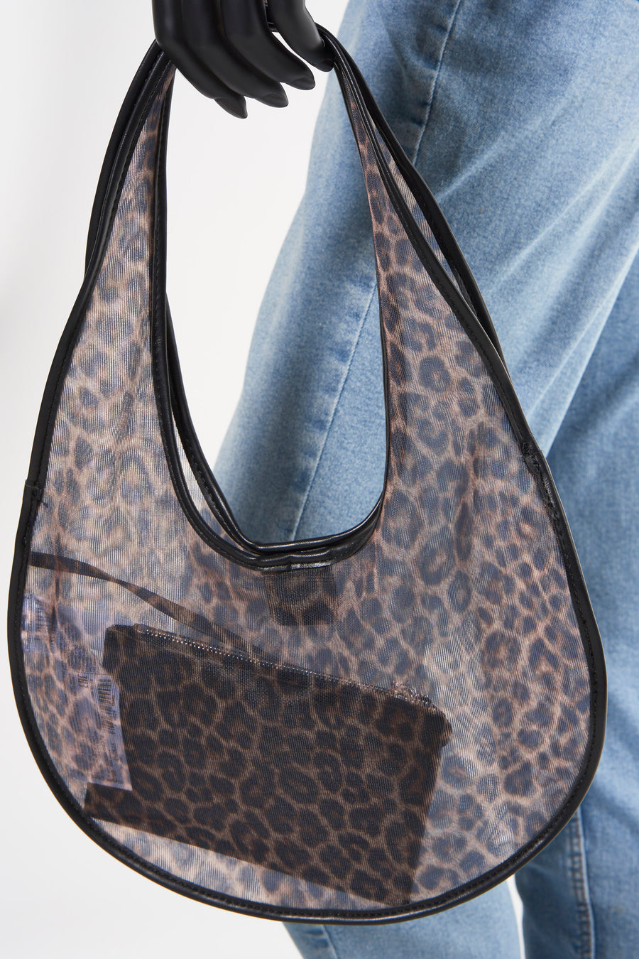Sac à main marron de MANGO avec un design imprimé léopard transparent et une finition noire, porté sur le bras.