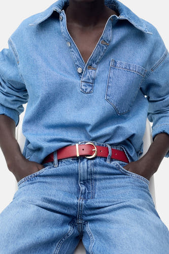 Ceinture rouge de MANGO, avec boucle dorée, portée avec une blouse en denim et des jeans.