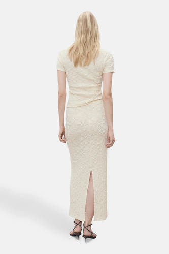 Longue jupe écru de MANGO, avec une fente à l'arrière et portée avec des sandales à brides.