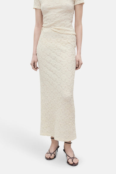 Lange ecru rok van MANGO, met een getextureerd bloemenpatroon en gecombineerd met zwarte sandalen.
