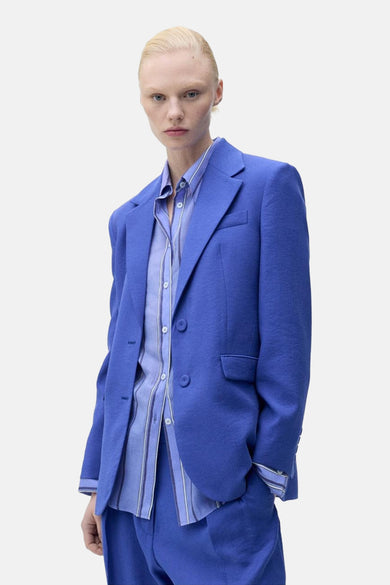 Blauwe blazer van MANGO, gedragen over een gestreept overhemd en bijpassende broek.