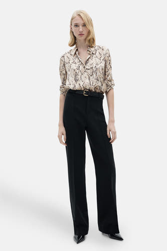 Chemise brune à longues manches de MANGO, avec imprimé serpent et portée avec un pantalon noir et une ceinture.