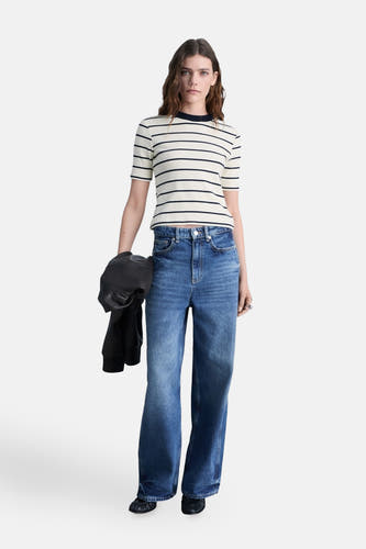 Wit gestreept T-shirt met korte mouwen van MANGO, gecombineerd met wijde jeans en een zwarte leren jas.