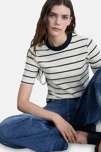 Wit T-shirt met korte mouwen van MANGO, met marineblauwe strepen en ronde hals, gecombineerd met een wijde jeans.

