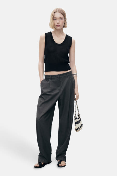 T-shirt noir de MANGO, sans manches et associé à un pantalon gris et un sac imprimé zèbre.