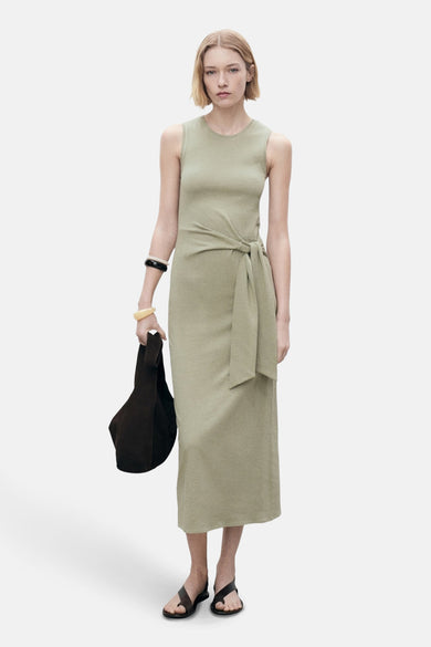 Mouwenloze khaki jurk van MANGO, met knoopdetail en accessoire-armbanden en tas.