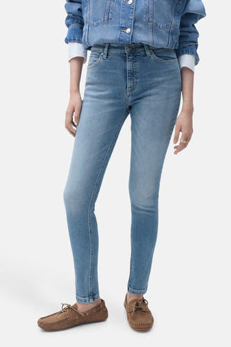 Skinny jeans van lichtblauw denim van MANGO, gecombineerd met een spijkerjack en bruine mocassins.