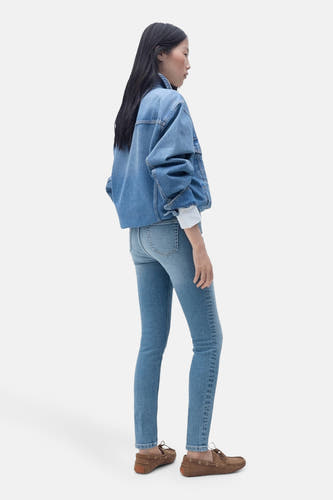 Skinny jeans van lichtblauw denim van MANGO, compleet met denim jack en bruine mocassins, zijaanzicht.
