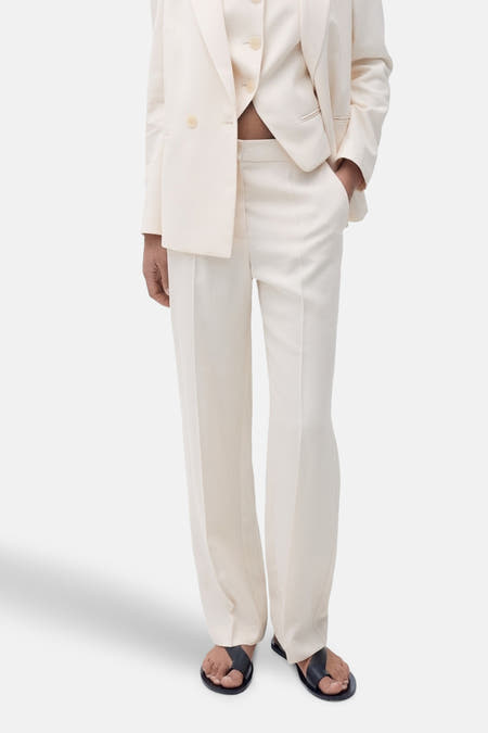 Beige kostuumbroek van MANGO, met een persplooi en wijd uitlopende pijpen, gecombineerd met een bijpassend vest en jasje.