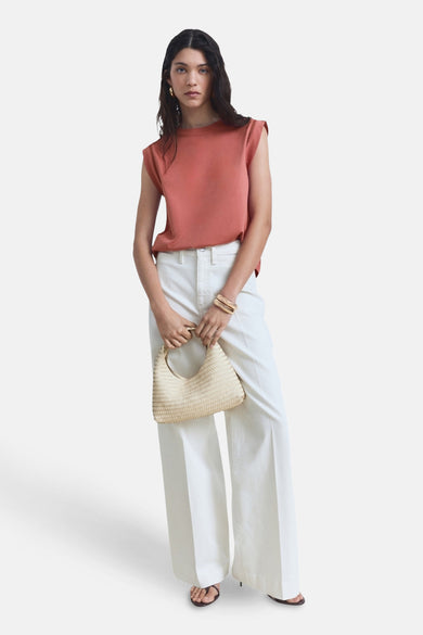 T-shirt rose sans manches de MANGO, porté avec un short blanc et une poche main en paille.
