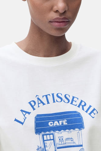 T-shirt blanc à manches courtes de MANGO, avec une impression bleue "La Patisserie Café" sur l'avant.
