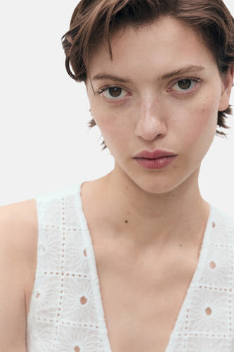 Witte mouwloze blouse van MANGO, met opengewerkte details en een verfijnd patroon.
