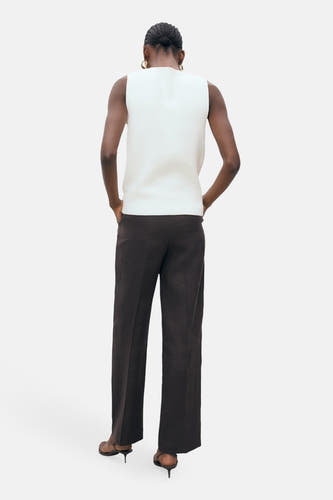 Blouse blanche sans manches de MANGO, vue de derrière, associée à un pantalon marron et des baskets marrons.