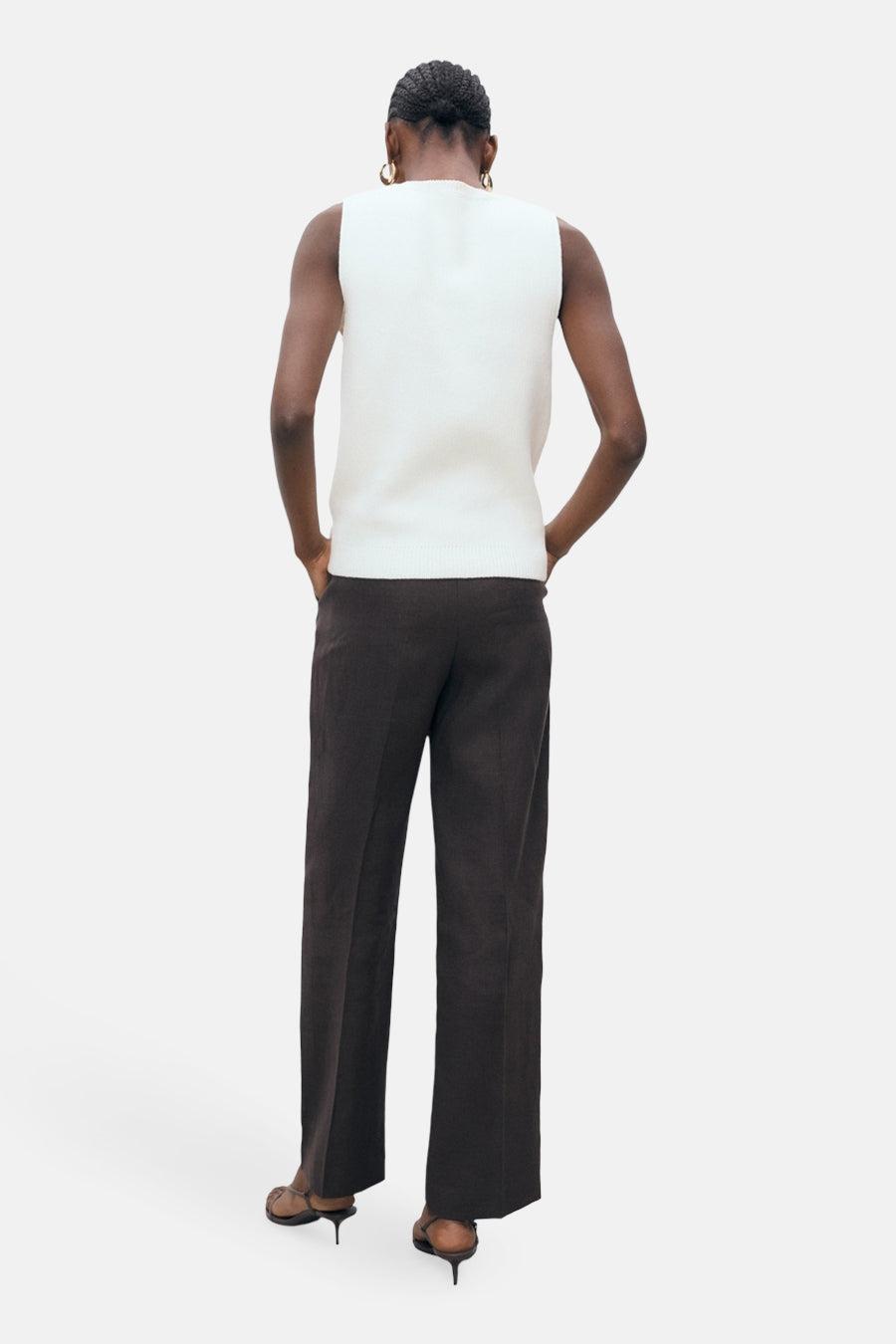 Blouse blanche sans manches de MANGO, vue de derrière, associée à un pantalon marron et des baskets marrons.