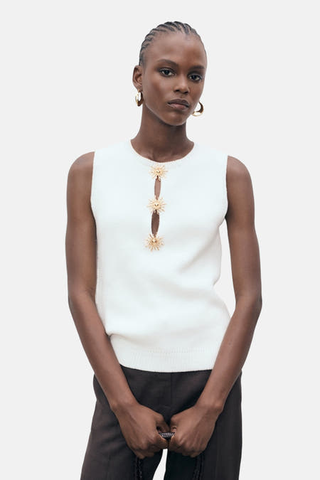 Witte mouwloze blouse van MANGO, afgewerkt met decoratieve gouden zonnetjes en een kleine opening aan de voorzijde.