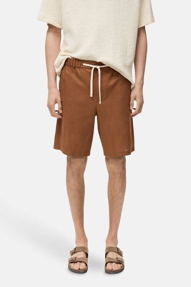 Short brun de MANGO, avec une cece bl et portéé un un-shirt crème et des sandales brunes.