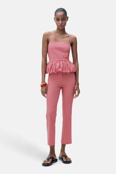 Rode mouwloze blouse van MANGO, met een gingham ruitpatroon en peplum taille, gecombineerd met een broek en sandalen.
