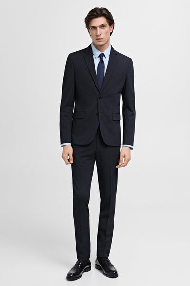 Blauwe blazer van MANGO, gedragen met een lichtblauw overhemd en een marineblauwe stropdas, met zwarte schoenen.