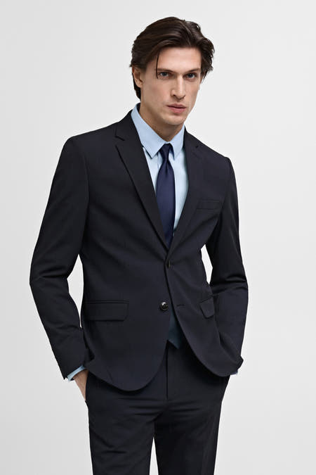 Blauwe blazer van MANGO, met een lichtblauw overhemd en donkerblauwe stropdas.