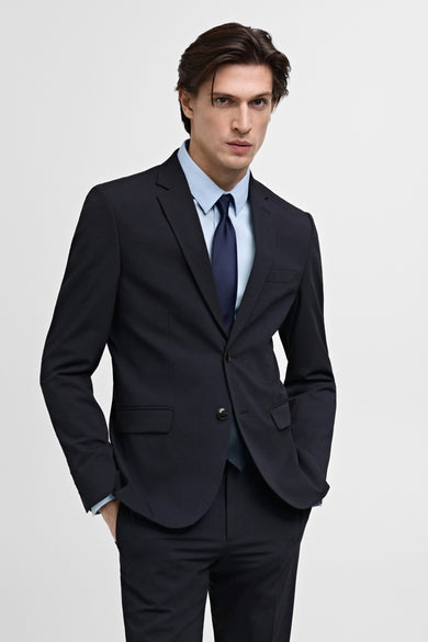 Blauwe blazer van MANGO, met een lichtblauw overhemd en donkerblauwe stropdas.