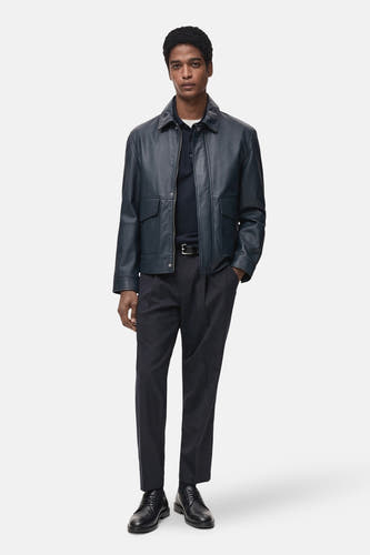 Pantalon de costume bleu MANGO, combiné avec un blazer en cuir bleu, une chemise à manches courtes bleu marine et des chaussures noires.