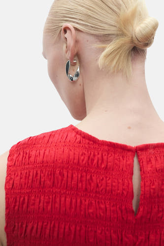 Jupe rouge sans manches de MANGO, avec une texture froncée sur le haut et une petite ouverture à l'arrière.