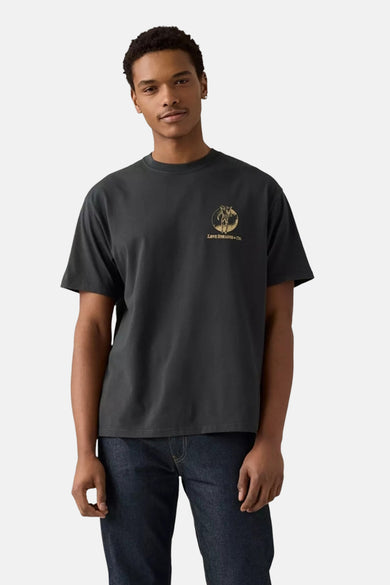 T-shirt gris à manches courtes de Levi's® avec une impression ronde du logo sur la poitrine, associé à des jeans foncés.