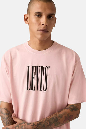 Roze T-shirt met korte mouwen van Levi's, met zwarte merklogo-opdruk, gedragen door model met tatoeages.