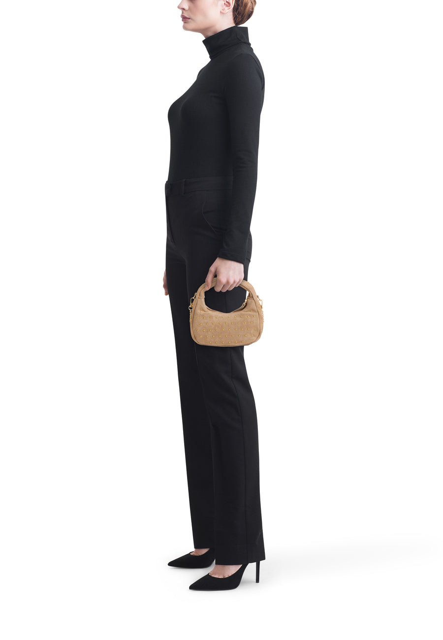 Beige handtas van Access® met goudkleurige studs en korte handgreep, vastgehouden door een model.
