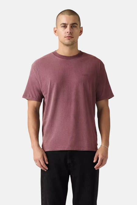 T-shirt rose à manches courtes de Levi's®, porté par un homme assis sur une chaise.