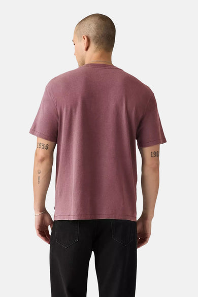 Roze T-shirt met korte mouwen van Levi's, gezien van achteren, met tatoeages op de armen en zwarte broek.