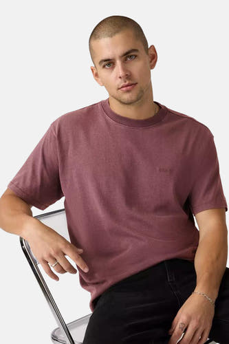 Roze T-shirt met korte mouwen van Levi's®, gedragen door een man die op een stoel zit.