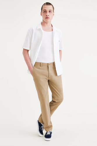 Beige chino van DOCKERS, gedragen met een wit hemd en een wit t-shirt, met blauwe schoenen.