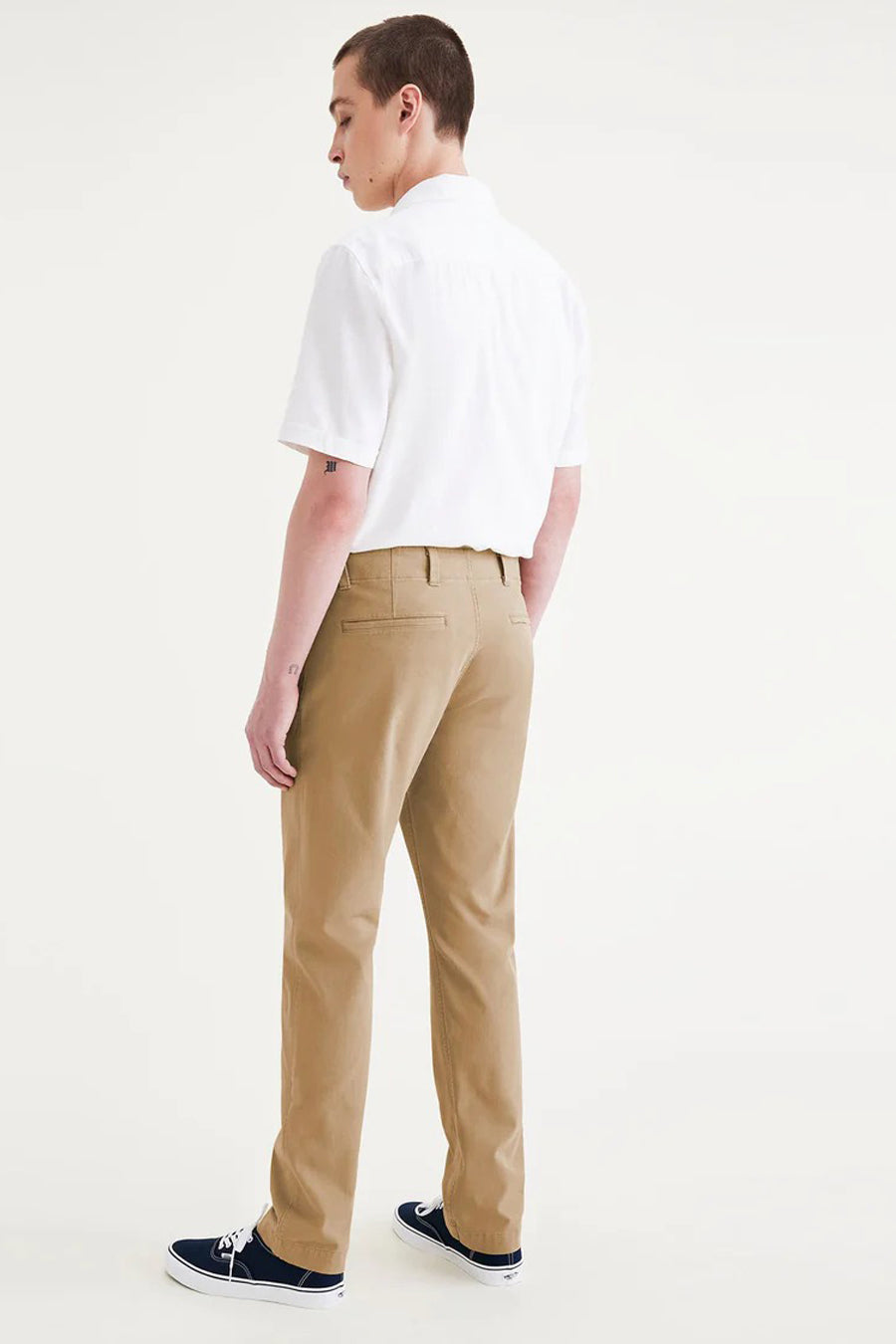 Beige chino van DOCKERS, gezien van achteren, gecombineerd met een wit overhemd en blauwe sneakers.
